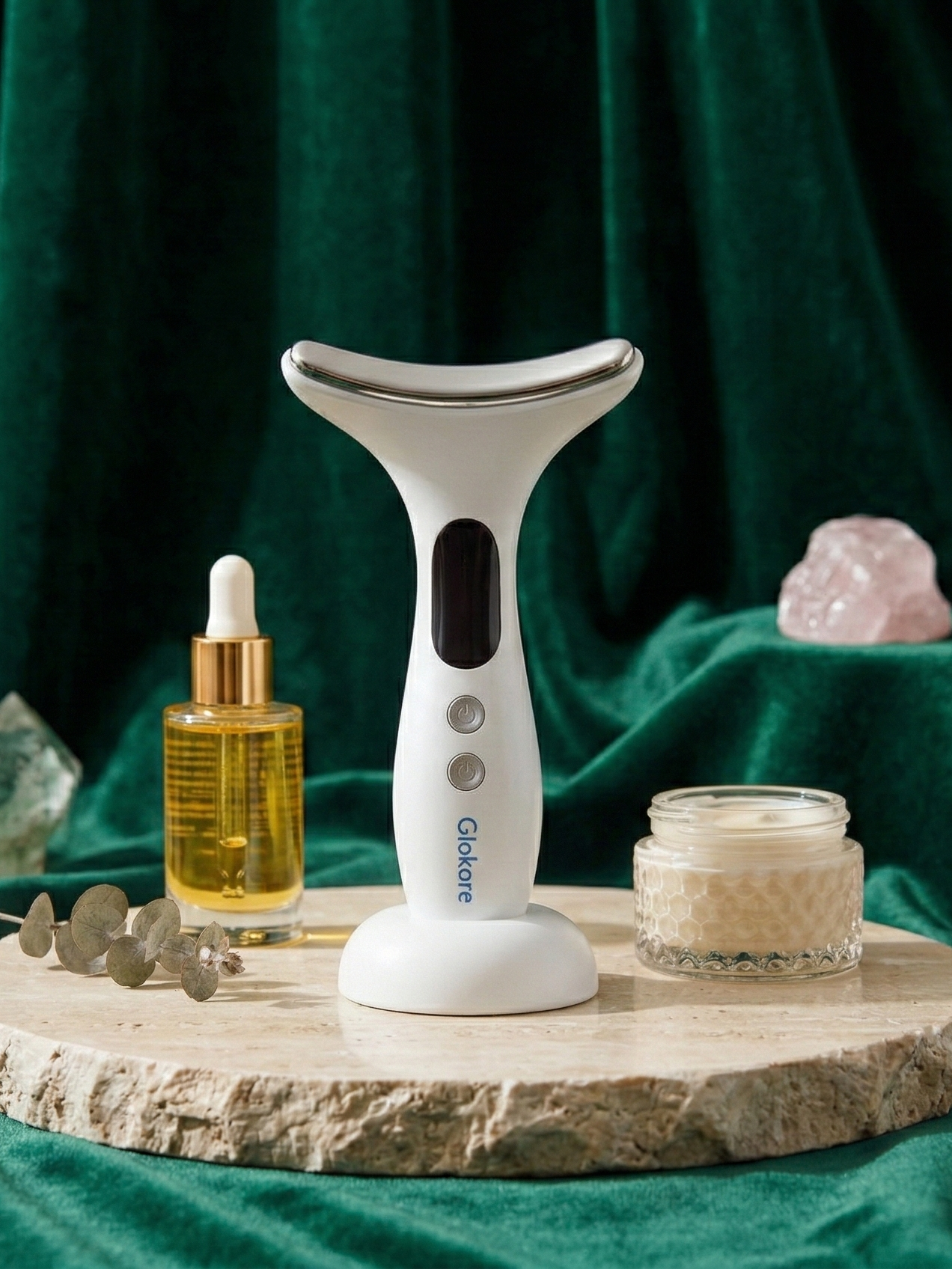 The Glokore Facial Sculptor stands clean and sharp on a spotless white pedestal in a bright bathroom environment, surrounded by subtle skincare items like serums and towels for a natural routine feel.