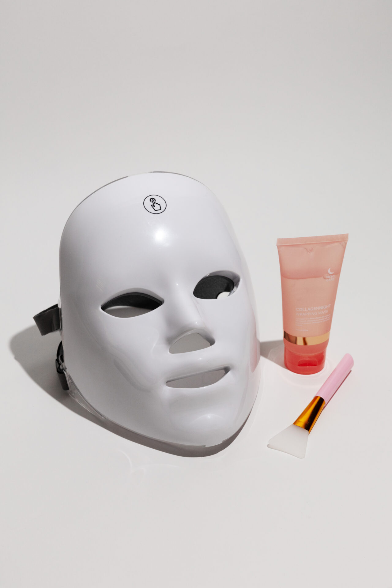 The GLOKORE Wireless LED Light Therapy Mask sits perfectly centered on a matte black background with a single spotlight above it — clean, dramatic, and evokes clarity in chaos.
